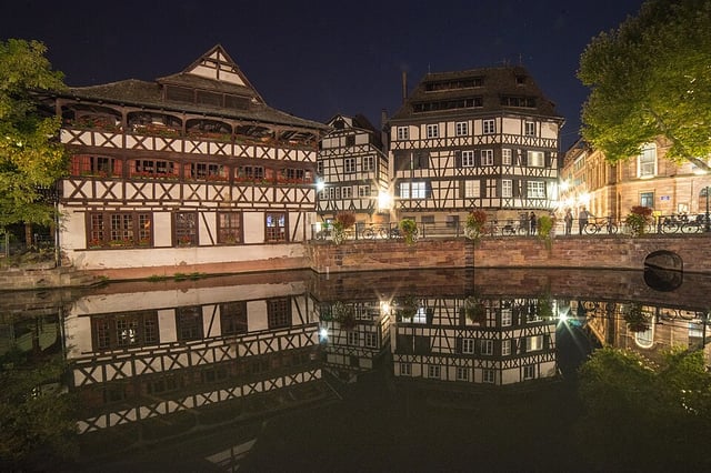 The half-timbered Maison des Tanneurs lit up at night, reflected in the canal below
