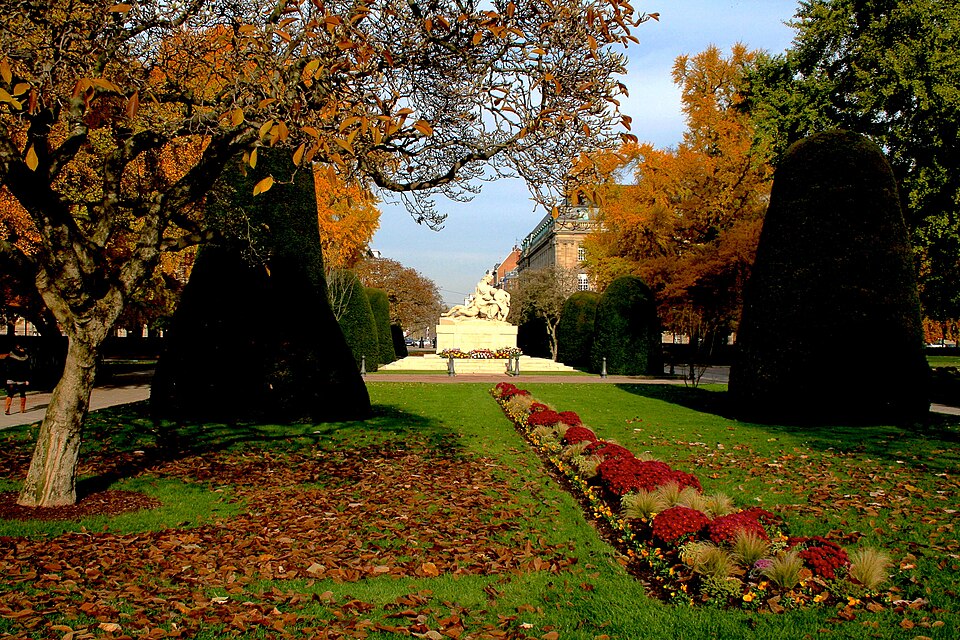 Autumn gardens on Place de la République, with clipped trees and a war memorial in the middle